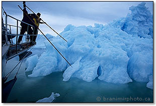 Sailors pushing a boat away from an iceberg