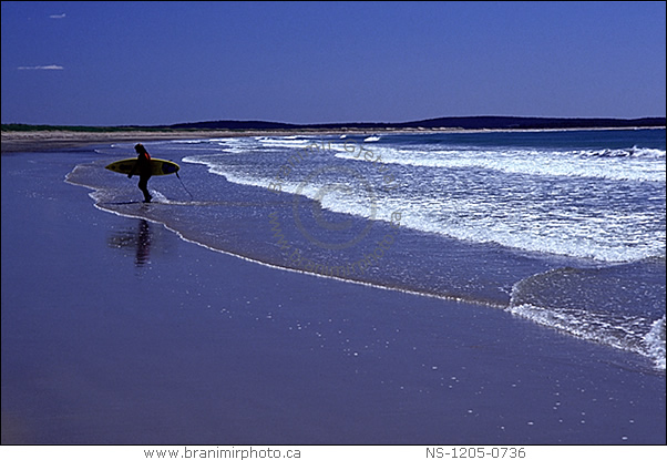 woman on beach with surfboard