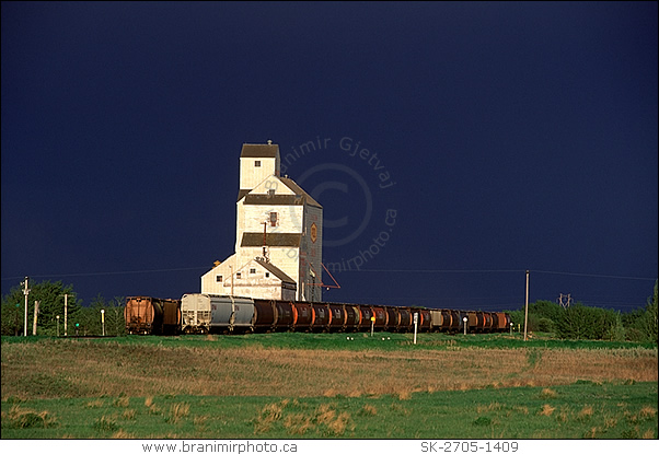 Freight train and grain elevator after storm, Saskatchewan